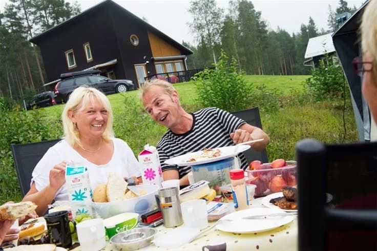 En utomhusborddukning på Skellefteå Camping med olika rätter och drycker omgivna av bekväma stolar.