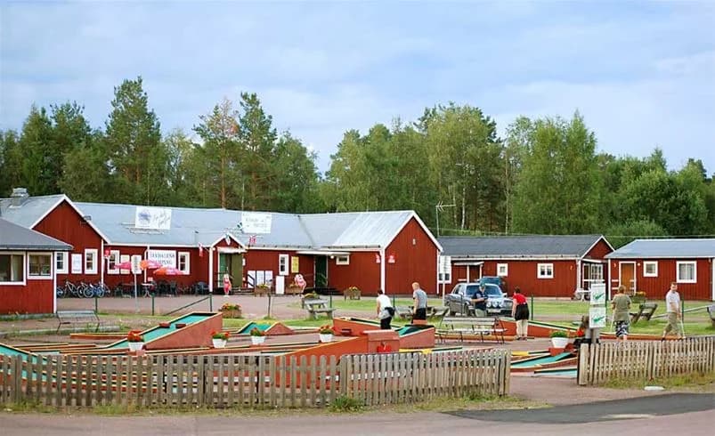 En grönskande campingplats i Älvdalen med öppna grönområden, stolar för avkoppling och rekreation under en solig dag.