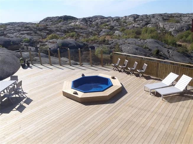 Interiörbild av en ljus, modern stuga med trägolv och träpaneler, möblerad för semesterboende på Hav & Logi Skärhamn.