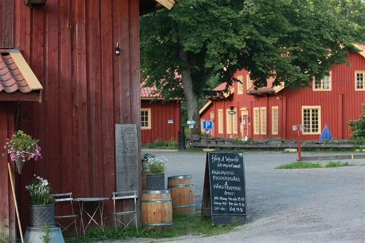 En mysig stuga med en trivsam uteplats som har bänkar och ett utebord, omgiven av en grönskande gård vid Hav & Logi Skärhamn.
