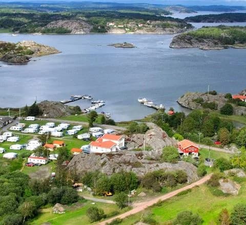 Flygbild över Malö Camping: en kustnära camping med båtar i bukten och en naturskön omgivning.