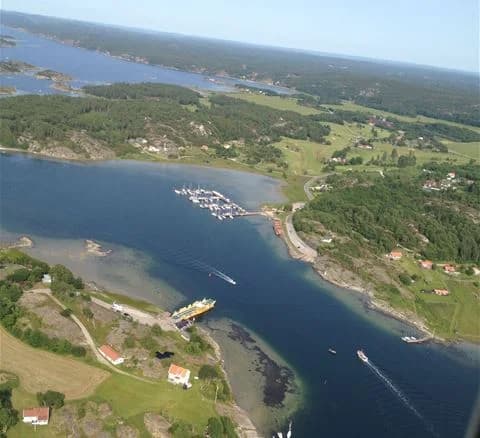 En naturskön vy vid Malö Camping med vatten i förgrunden och båtar längs kusten.