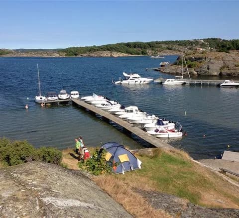 En motorbåt ligger förtöjd vid en brygga vid Malö Camping, omgiven av stilla vatten och en pittoresk kustlinje.