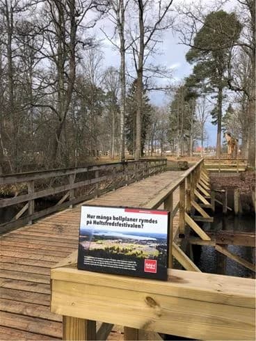 Alt-text: En träbro eller promenadbrygga över ett våtmarksområde vid Hultsfred Strandcamping.