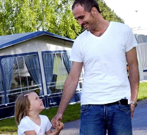 En glad familj njuter av sin semester på Gustavsvik Resort, med skratt och lek vid poolområdet.