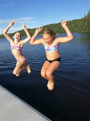 Personer njuter av en solig dag vid vattnet iklädda badkläder på Degernäs camping, engagerade i roliga och avkopplande aktiviteter.