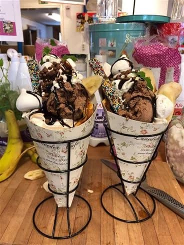 En närbild på en glasstruck vid Degernäs camping. Flera olika glassorter och -smaker presenteras i en glassmeny. I förgrunden syns färgglada glassar i strutar, perfekt för en sommardag.