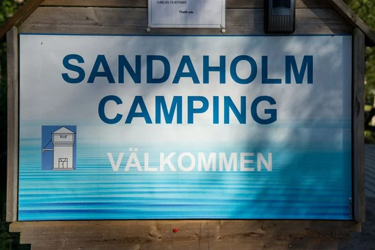 En campingplats med flera tält och mindre byggnader omgivet av grönska vid Sandaholm Restaurang & Camping.
