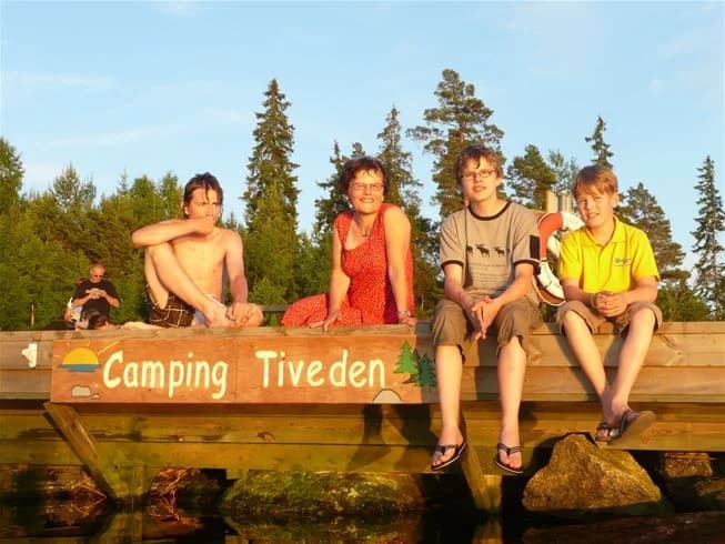 En grupp människor campar i en naturskön miljö vid Tiveden, engagerade i utomhusaktiviteter och njuter av sin semester i naturen.