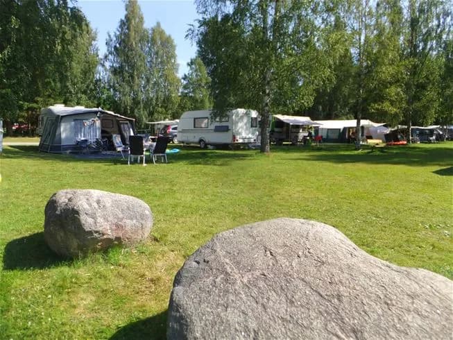 En tältplats i en grönskande park med träd i bakgrunden, perfekt för rekreation och avkoppling i naturen.