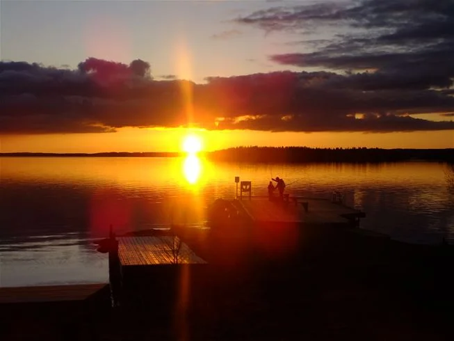 En vacker solnedgång vid Camping Tiveden, där himlen är färgad i varma orange och rosa toner. Naturen omger horisonten och skapar en lugn och fridfull atmosfär.