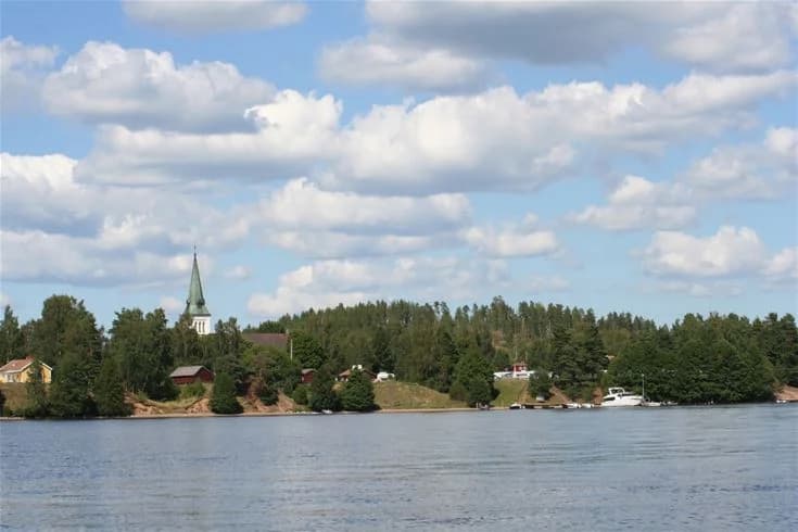 En naturskön bild av Malexander camping med en rofylld utsikt över vattendraget omgivet av lummiga träd.