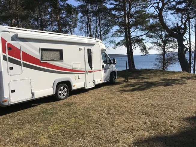 En husbil parkerad på Malexander camping, omgiven av grönska, redo för en roadtrip.