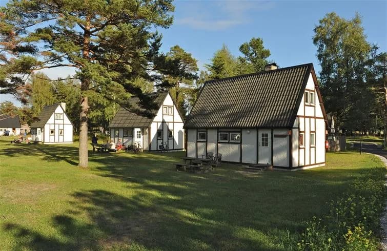 Bild på Sudersand Resort: En charmig stuga omgiven av frodig grönska med träd och välskött gräsmatta. Området är vackert anlagt och ger en inbjudande och lantlig atmosfär, perfekt för avkoppling och naturupplevelser.