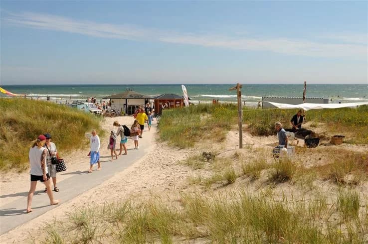 En solig sommarstrand med blått hav och gyllene sand vid Sudersand Resort, perfekt för avkoppling och semester.