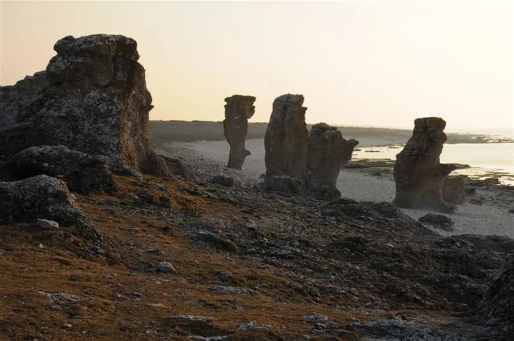 En karg och dramatisk kustlinje vid Sudersand Resort med framträdande geologiska formationer och berggrund som bildar en monolit mot horisonten.