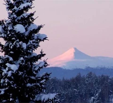 Snötäckt campingplats vid Särna med utsikt över bergiga landskap och vinterklädd gran- och furuskog.