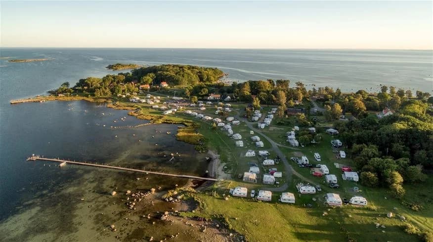 Flygfoto över Landöns camping vid kusten. Bilden visar en naturskön plats med hav, kustlinje och en ö i bakgrunden.