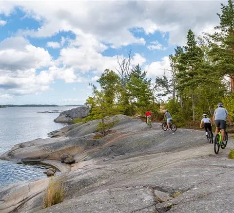 En cykel står parkerad vid stranden vid Gålö havsbad, med utsikt över vattnet och den omgivande kusten. Perfekt för avkopplande aktiviteter och cykelturer i naturskön miljö.