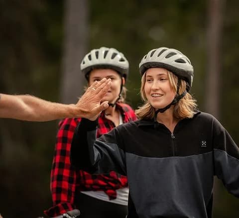 Person som ler och bär cykelhjälm vid Gålö havsbad, i en avslappnad och glad semesteratmosfär.