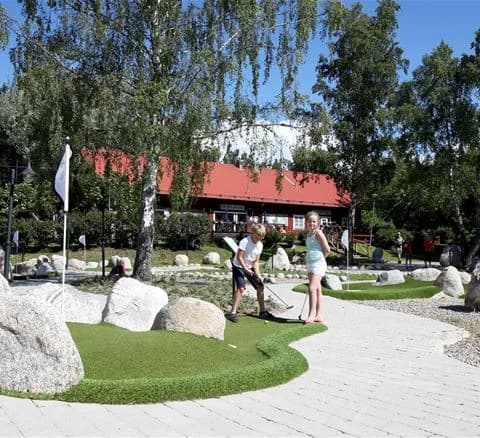 En naturskön plats vid Gålö Havsbad med stenar och gröna gräsmattor, idealisk för rekreation och avkoppling i en parkmiljö. Trädgårdsliknande landskap med flaggstenar och öppna ytor.