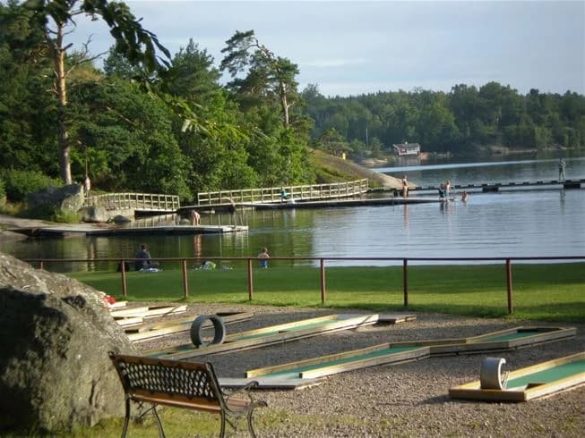 En sjönära campingplats med brygga och gångväg, omgiven av frodig grönska, perfekt för rekreation och avkoppling vid vattnet.