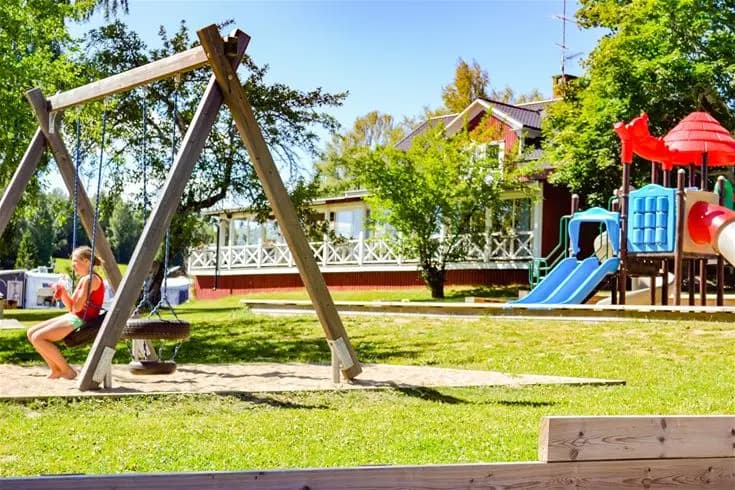 Lekplats vid Charlottenberg camping & stugor - Haganäset, med rutschkana och övrig lekutrustning i en öppen rekreationsmiljö.