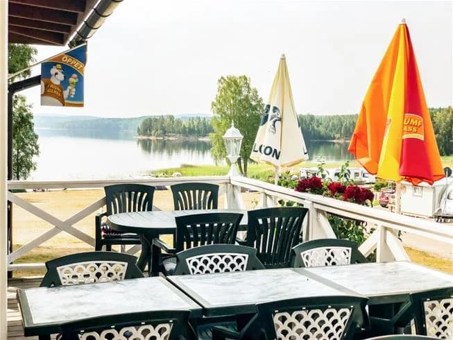 Utomhusscen vid Charlottenberg camping & stugor - Haganäset med trädgårdsmöbler och parasoller, vilket skapar en inbjudande plats för avkoppling och måltider utomhus.