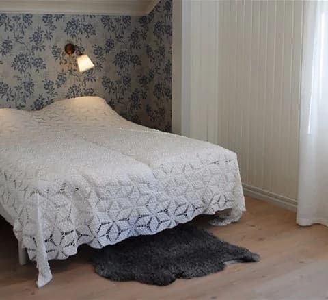 En inbjudande sovrumsmiljö på Anfasteröd Gårdsvik med en mjukt bäddad säng, ljusa sängkläder och textilier samt ett stilrent golv.