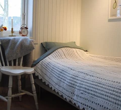 Ett mysigt sovrum på Anfasteröd Gårdsvik, med trämöbler och en säng bäddad med vita lakan, som ger en inbjudande atmosfär.