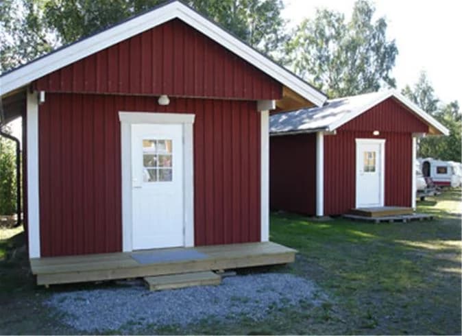 En mysig kursgård med stugor och träd, omgiven av grönska och välskött trädgård.