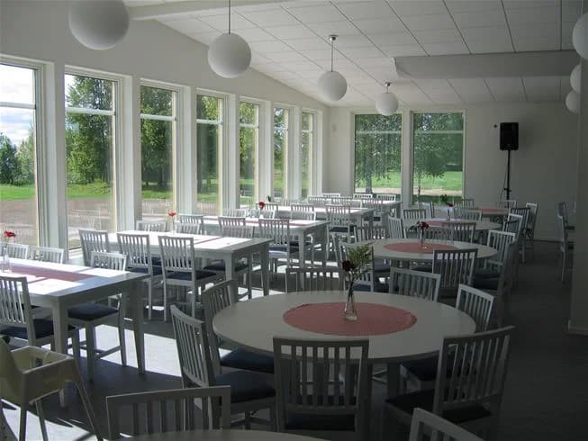 Bild av Storstrand kursgård som visar en grönskande utomhusmiljö med utemöbler och gräs. I bakgrunden syns byggnader som kan användas som restaurang eller cafeteria.