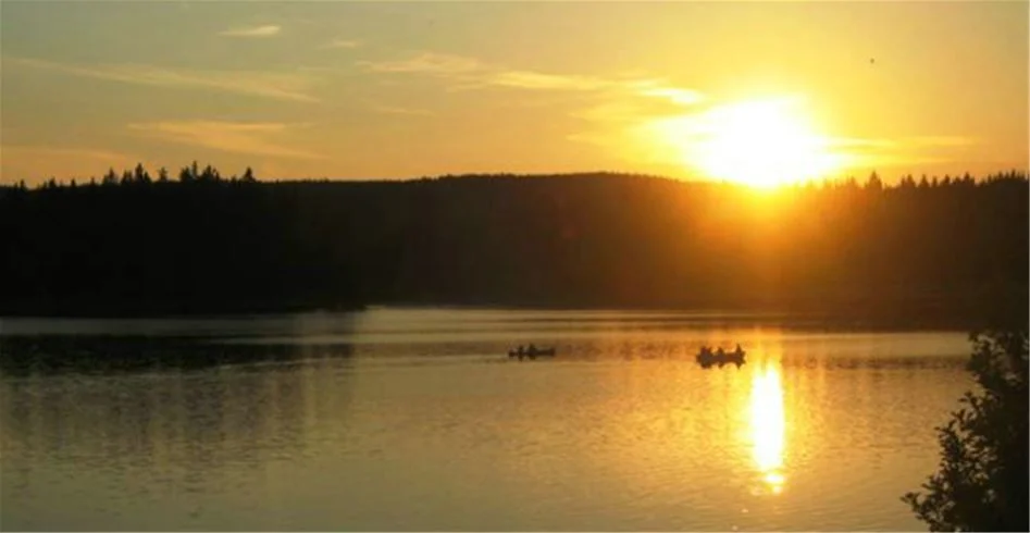 En vacker solnedgång vid en sjö, omgiven av grönskande landskap och lugna vatten vid Sölje Camping.