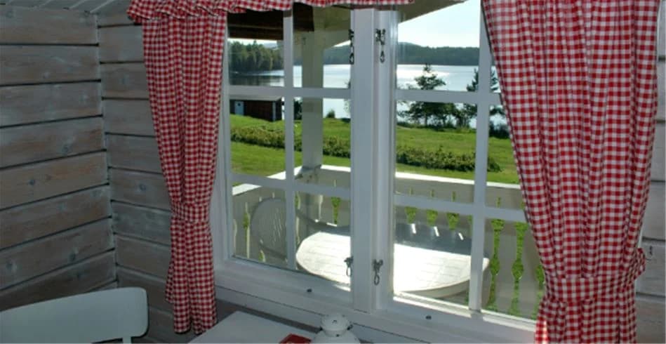 Utomhusmiljö på Sölje Camping med trämöbler och en hängmatta på en veranda. Solskydd i form av gardiner och växter som dekoration ger en avkopplande atmosfär.