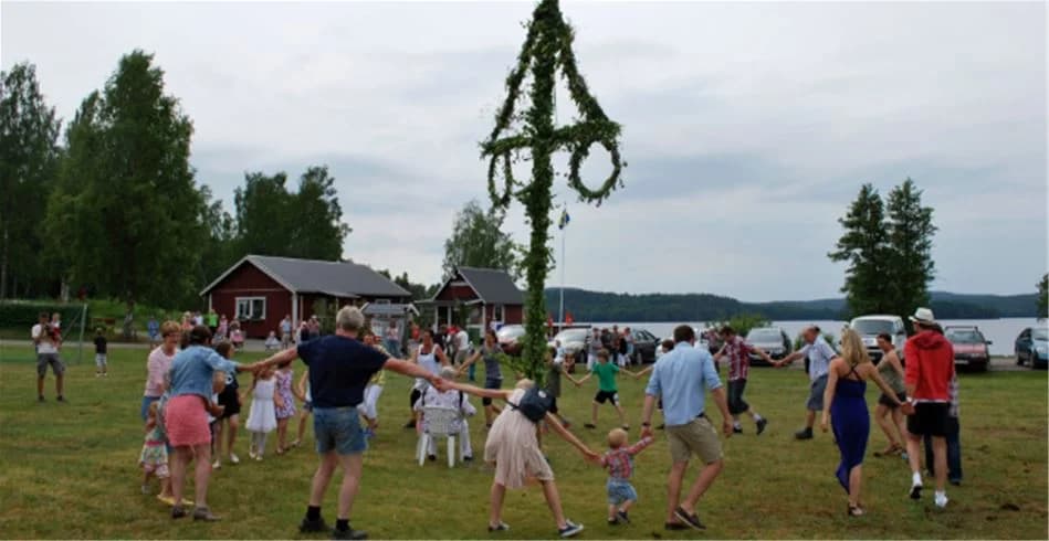 En livlig campingmiljö vid Sölje Camping med besökare som njuter av fritidsaktiviteter och gemenskap i solen. Tält och husbilar syns i bakgrunden, medan familjer deltar i festival-liknande evenemang med uppträdanden och aktiviteter.