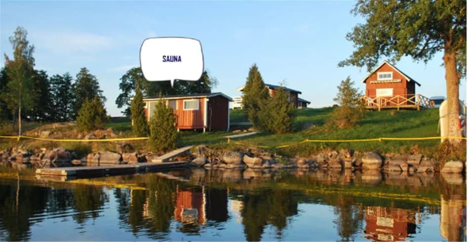 En trästuga vid kanten av Sölje Camping, omgiven av lummig grönska och lite solsken.