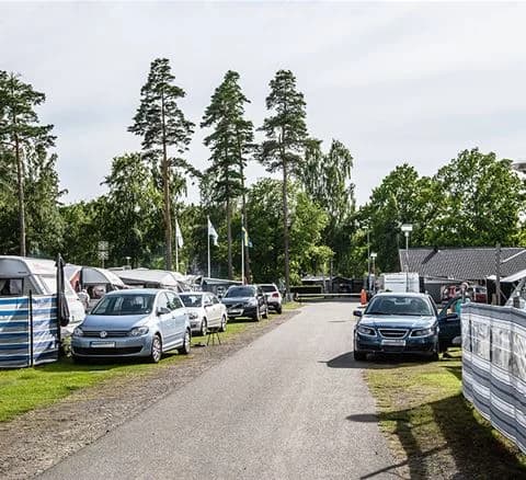 En bil står parkerad på grusplanen framför Bromölla Camping & Vandrarhem.