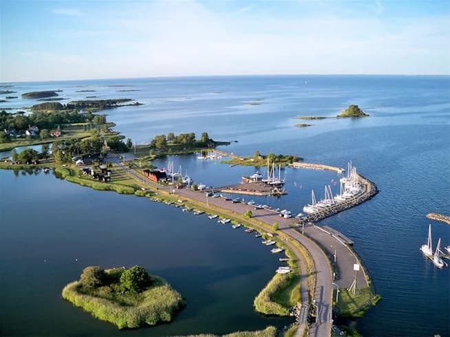 Vy över ett kustnära område vid Dalskärs camping, där havet möter land. Vattnet sträcker sig långt ut i horisonten och omges av naturliga kustområden, vilket ger en fridfull och naturskön miljö.