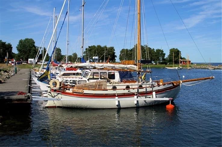 Bild av Dalskärs camping med flera båtar förtöjda vid en småbåtshamn. Båtarna ligger i det stilla vattnet under en klar himmel, och segelbåtarnas master sträcker sig upp mot horisonten.