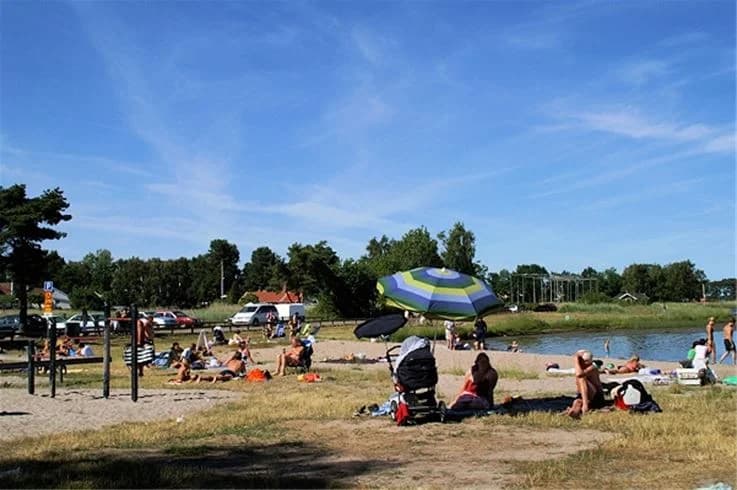 En solig sommardag på Dalskärs camping med människor som njuter av stranden och fritidsaktiviteter vid kusten.