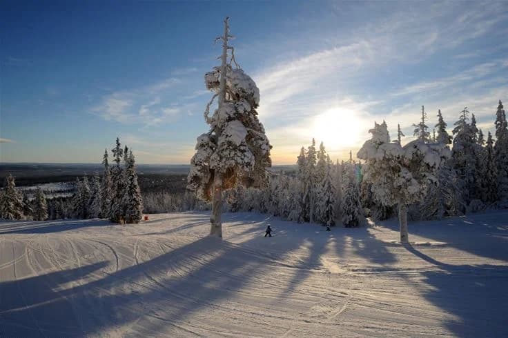 En vintermorgon på Idre Fjäll camping med snöklädda fjäll i bakgrunden och solens första strålar som lyser över den frostiga marken.