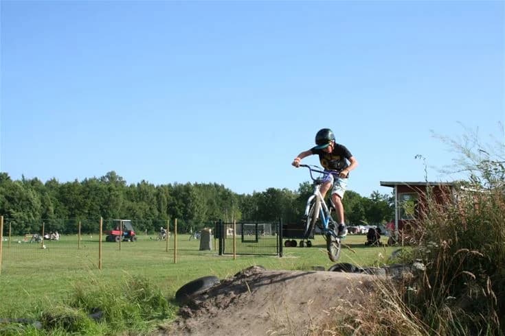 En cykel parkerad vid en campingområde i Saxnäs, med fokus på cykelns hjul, däck och styre. I bakgrunden syns campingmiljön vilket antyder en plats för utomhusaktiviteter och rekreation.