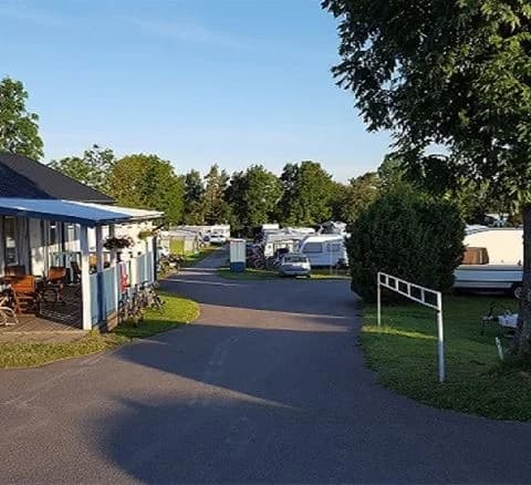 En översiktsbild av Klinta camping som visar en parkeringsplats med husbilar och husvagnar. Området är omgivet av grönska, vilket skapar en inbjudande och avkopplande atmosfär för besökare.