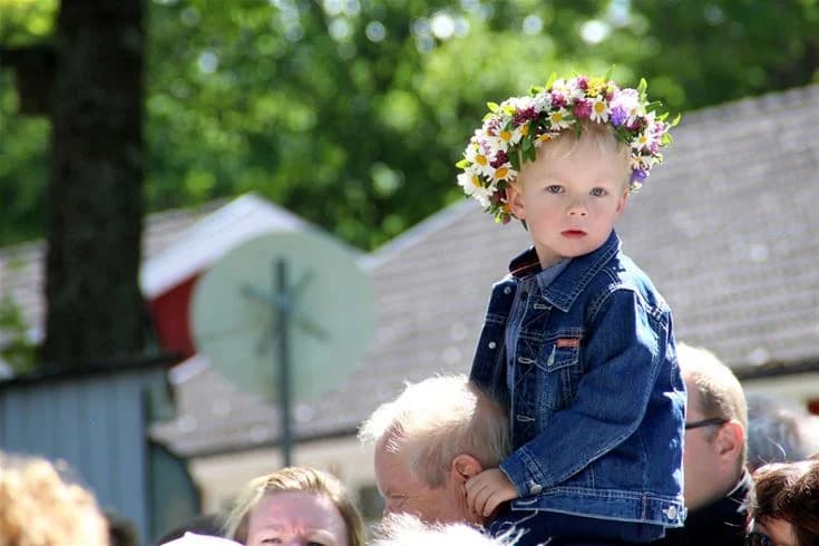 Ett litet barn med blont hår leker i vårmiljö på Eksjö Camping & Konferens, omgiven av blommor och i färgglada vårkläder.