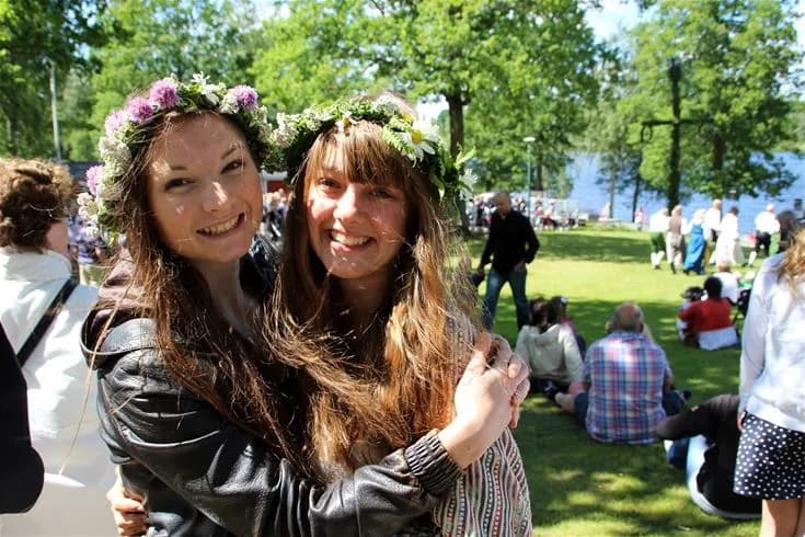 En grupp människor skrattar och njuter av en solig vårdag utomhus vid Eksjö camping & konferens, mitt i naturen, omgivna av grönska och glädje.