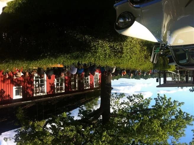 En landskapsvy vid Eksjö Camping & Konferens med en stilfull kit car i förgrunden, där bilens bakljus tydligt syns.