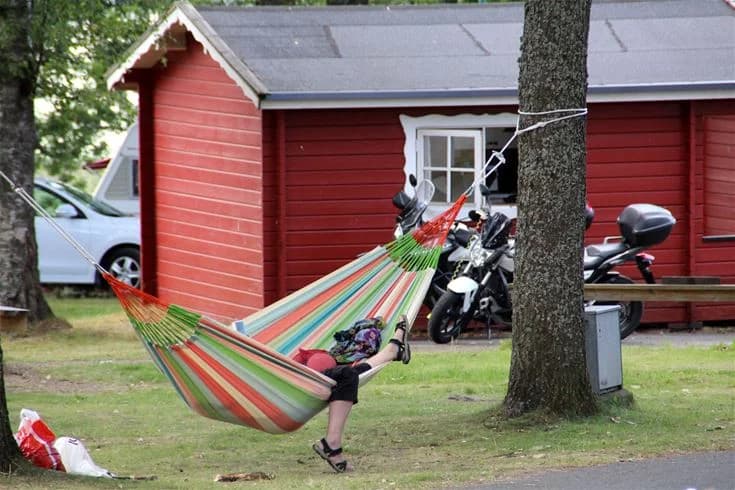 En grönskande campingplats med välklippta gräsmattor och skuggiga träd, som ger en inbjudande känsla av sommar och semester.
