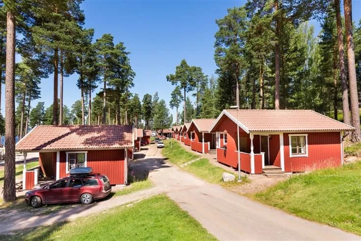 En idyllisk vy över en lantlig stuga vid Leksand Resort, omgiven av grönskande natur och sluttande marker.