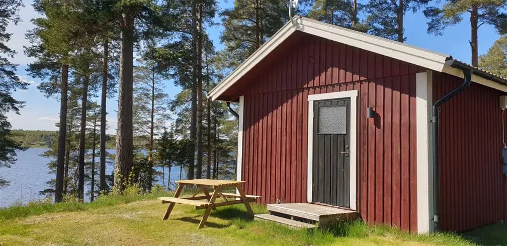 En mysig stuga i trä omgiven av en frodig skog, belägen på Leksand Resort.