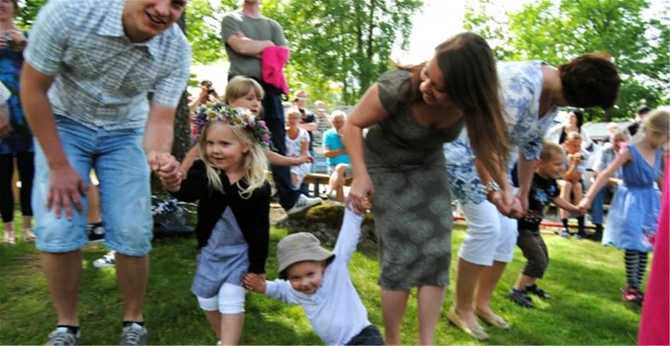 Ett glatt sällskap människor i ledig klädsel, inkl. jeans, umgås vid Eksjö Camping & Konferens under en solig dag. De ser ut att ha roligt och njuta av utomhusaktiviteterna.